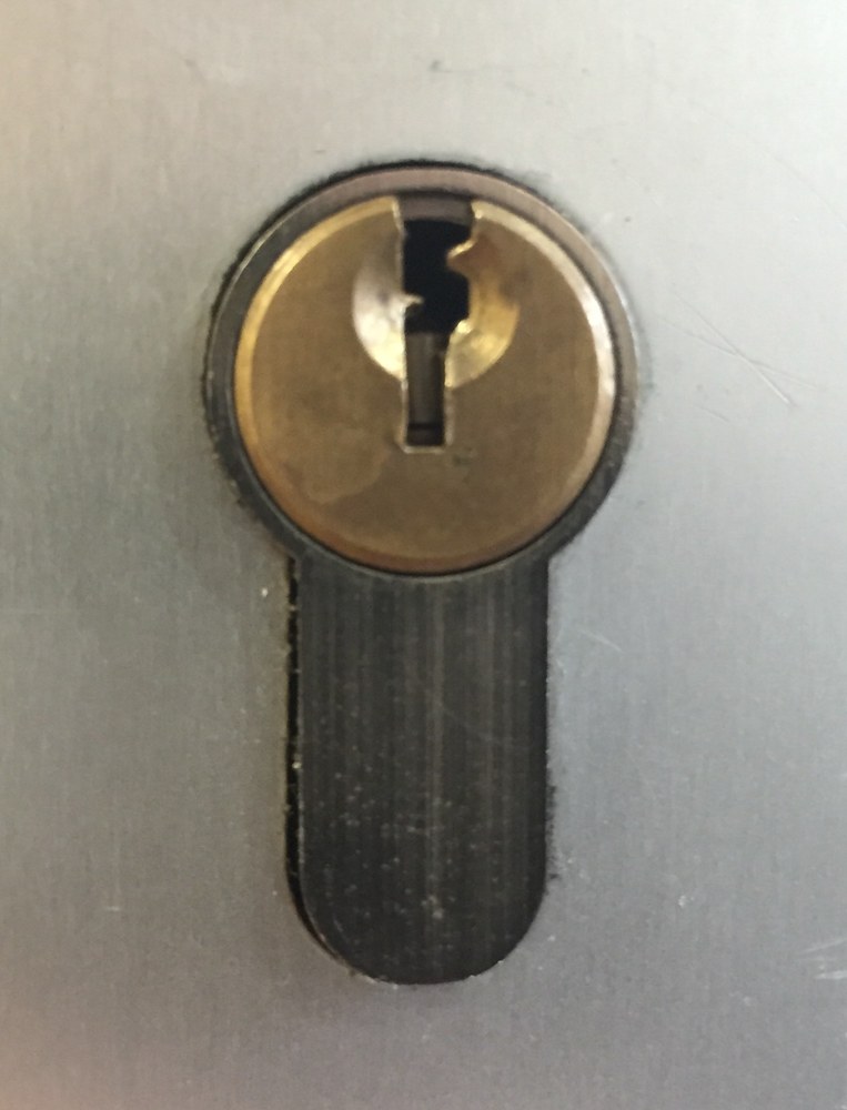 Cylindre de serrure métallique à profil européen vu de face, avec entrée de clé et corps allongé.